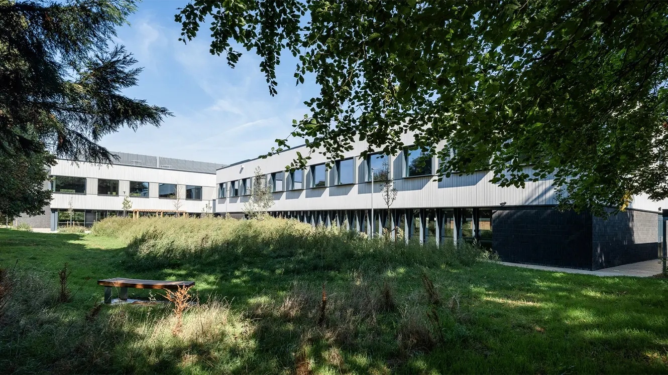 Vue extérieure de The Press, campus des sciences de la vie et de l’innovation à Foxton, Cambridge, entouré d’arbres et d’aménagements paysagers.